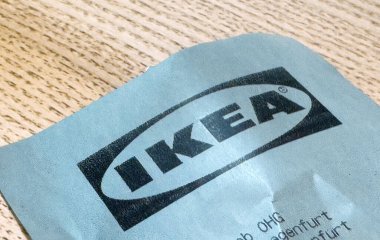 Buruşuk bir kağıdın üzerindeki IKea logosunun ahşap arka plana yakın plan görüntüsü..