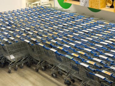 Mağaza koridorunda sıra sıra boş alışveriş arabaları.