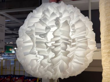 Modern iç mekânda ışıklandırılmış zarif, beyaz, fırfırlı kumaş bir abajur..