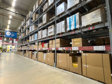 Yığınlanmış kutular ve parlak ışıklandırma birimleriyle dolu büyük depo koridoru..