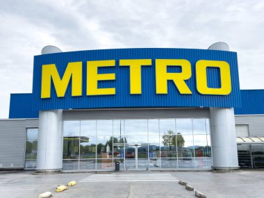 Şehir merkezindeki mavi ticari bina cephesinde büyük bir metro tabelası.