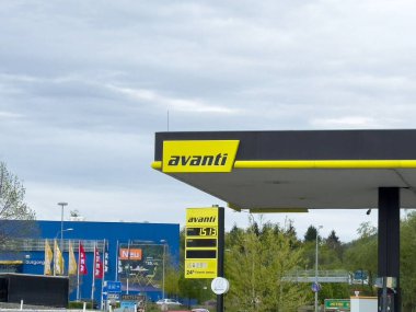 Şehir ortamında bulutlu gökyüzü ve yeşilliğe karşı Avanti benzin istasyonu işareti.