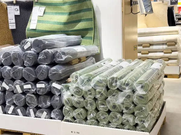 Toptan mağaza koridorunda yığılmış halı ruloları farklı renk ve desenlerle.