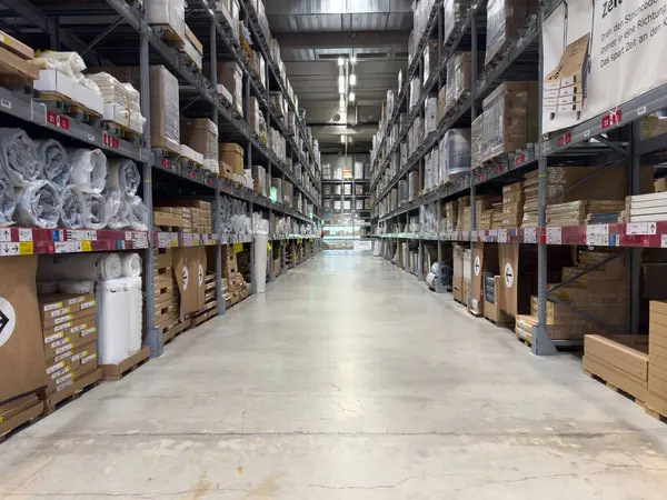 Endüstriyel raflarda istiflenmiş kutular ve paletlerle dolu geniş depo koridoru..