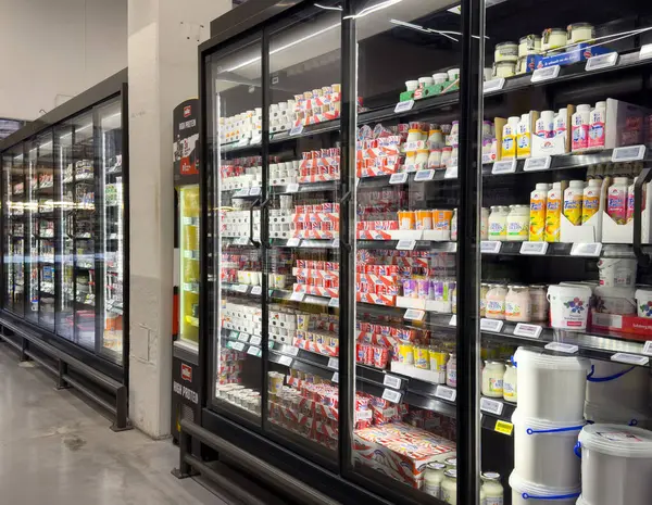 Süt ürünleri süpermarket buzdolabı koridorunda süt, yoğurt ve peynir çeşitleriyle sergileniyor..