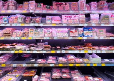 Çeşitli paketlenmiş etlerle süpermarket et koridoru görüntüsü.