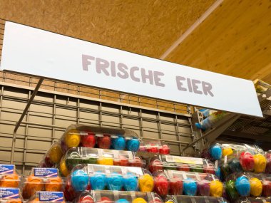 Alman pazarındaki 'Frische eier' tabelasının altında sergilenen renkli yumurta kutuları.