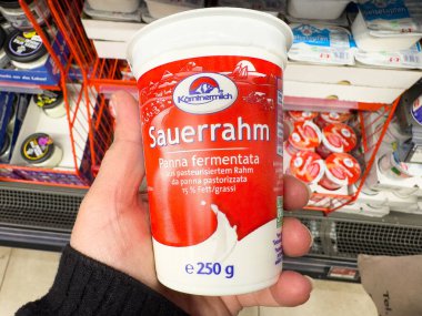 Süpermarket mandıra koridorunda 250 gramlık sauerrahm bardağı tutuyor..