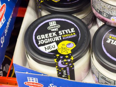 Alman süpermarketinde vanilya ve yabanmersini aromalı Yunan stili jogurt paketleme.