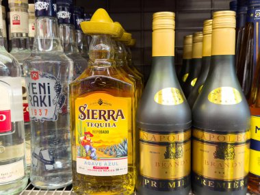 Bir mağazanın rafında çeşitli içki şişeleri var. Tekila ve konyak çeşitleri sergileniyor..