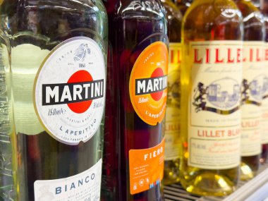 Rafta çeşitli martini şişeleri ve küçük aperatifler var..