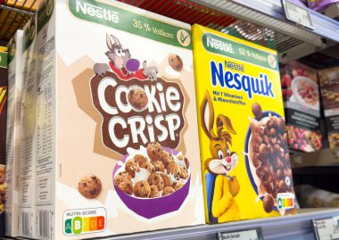 Yuvarlak mısır gevreği kutuları gösterimi: Süpermarket rafında çıtır çıtır kurabiye ve nesquik.