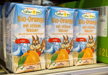 Süpermarketin rafında organik portakal aromalı su kutuları.