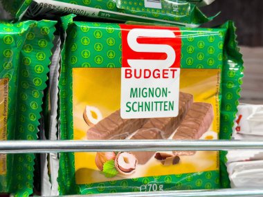 Mignon raftaki yeşil ambalajda çikolatalı fındıklı çikolatayı şinitliyor.