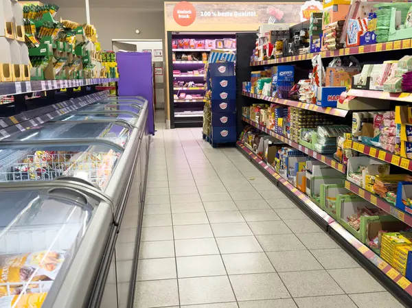 Modern bir süpermarkette rafa kaldırılmış ürünler ve donmuş gıdalarla dolu bir market koridoru..
