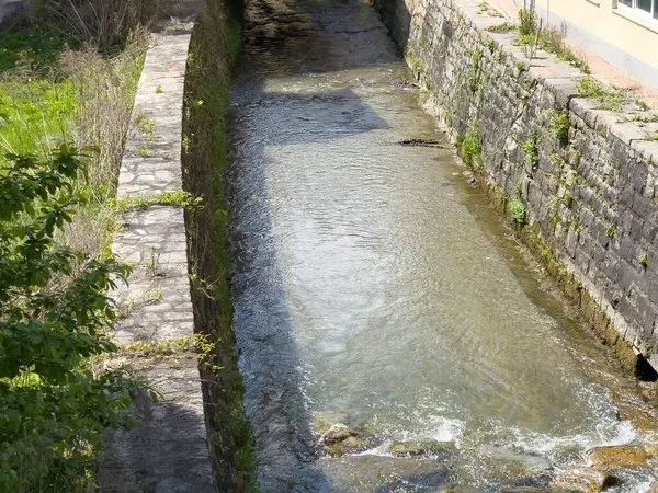 Yeşil şehir ortamında akan suyla taştan kanallar..