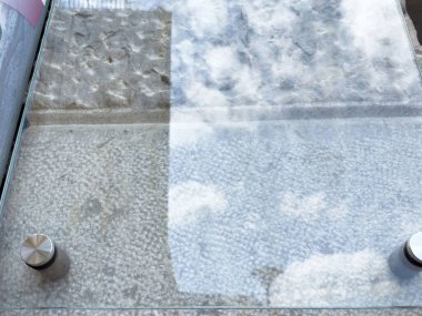 Şeffaf cam zemin, taş ve bulut yansımaları..