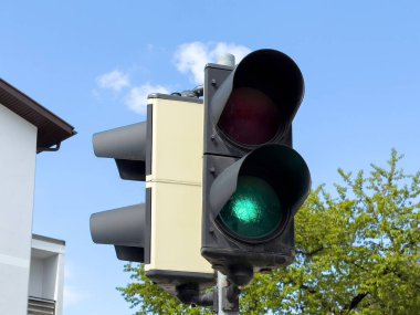 Mavi gökyüzüne karşı yeşil ve kırmızı ışıklı açık hava trafik lambası.