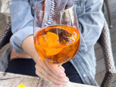 Kafkasyalı yetişkin kadın tarafından tutulan şarap kadehinde aperol spreyi ferahlatıcı..