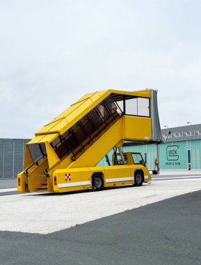 Asfalt üzerinde sarı mobil havaalanı yolcu merdiveni.
