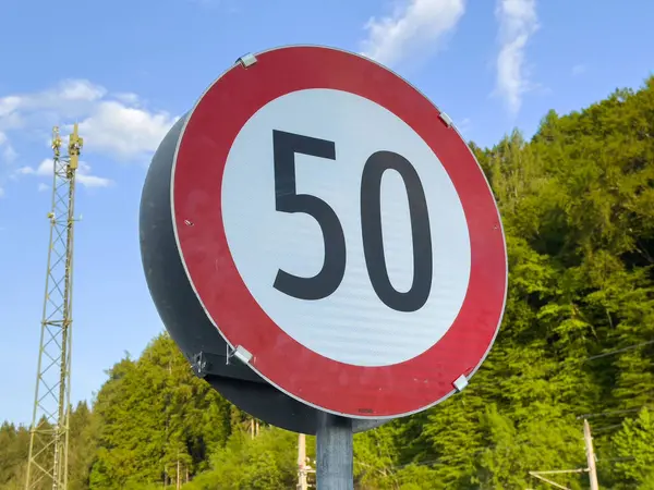 Bereketli yeşil orman arka planına karşı saatte 50 km hız sınırı işareti.
