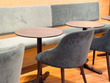 Yuvarlak masaları ve döşeli sandalyeleri olan modern bir kafe..