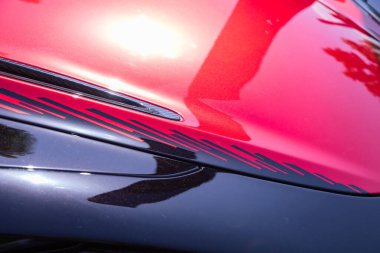 Velden, Avusturya - 22 Haziran 2024: Parlak yüzey ve tasarım unsurlarını vurgulayan Sportwagenfestival 'de kırmızı ve siyah bir spor araba kaputunun yakın görüntüsü