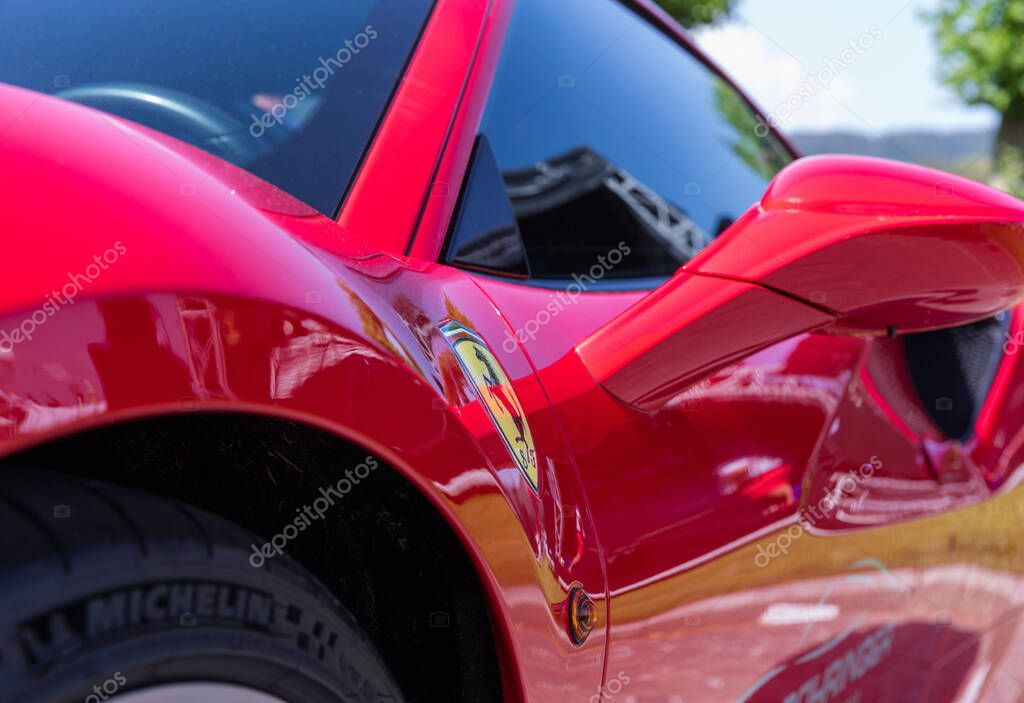 Velden, Austria - June 22, 2024: Ferrari sports car displayed at Sportwagenfestival, highlighting its glossy red finish and distinctive logo under bright sunlight