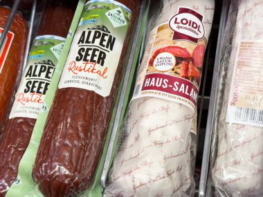 Villach, Avusturya - Mayıs 06, 2025: Alpen Gören rustik sosis ve Loidl Haus-Salami, benzersiz ambalaj ve dokularını vurgulayarak bakkalda güzelce düzenlenmiştir.