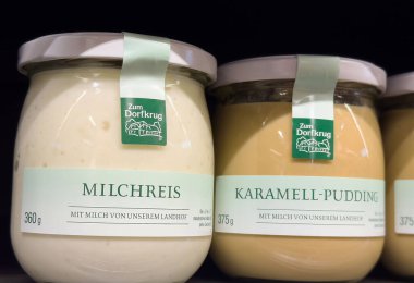 Villach, Avusturya - Mayıs 06, 2025: Süpermarket rafındaki Zum Dorfkrug 'dan Milchreis ve Karamell-Puding kavanozları, kremsi dokuları ve davetkar etiketleri vurguluyor