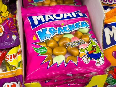 Villach, Avusturya - 06 Mayıs 2025: MAOAM Kracher şeker paketi çeşitli şekerlemelerle dolu bir mağaza rafında belirgin bir şekilde sergilenen renkli çiğneme şekerleri içeriyor