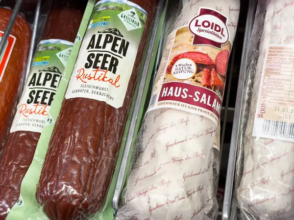 Villach, Avusturya - Mayıs 06, 2025: Alpen Gören rustik sosis ve Loidl Haus-Salami, benzersiz ambalaj ve dokularını vurgulayarak bakkalda güzelce düzenlenmiştir.