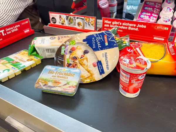 Villach, Avusturya - 06 Mayıs 2025: SPAR süpermarketinin kasasında sergilenen yoğurt, peynir ve pizza gibi çeşitli market ürünleri