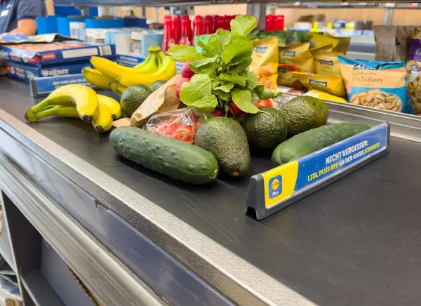 Villach, Avusturya - Mayıs 06, 2025: Arka planda canlı ambalaj ile marketteki taşıma bandında taze meyve ve sebzeler sergilendi