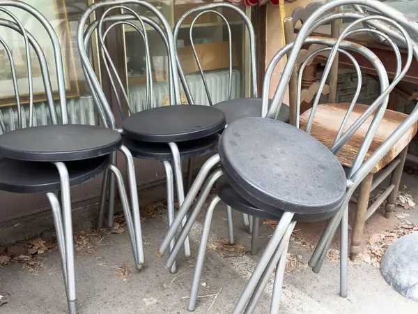 Yığılmış metal ve ahşap sandalyeler, eğimli sırtlar ve yuvarlak koltuklar..