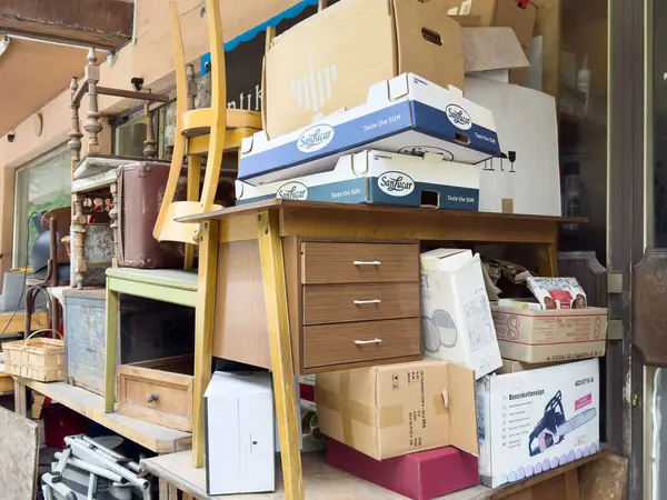 Yığınla mobilya ve çeşitli kutularla dolu dağınık bir açık hava deposu..