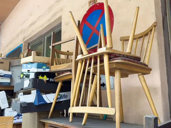Masaya istiflenmiş eski tahta sandalyeler karton kutularla çevrili..