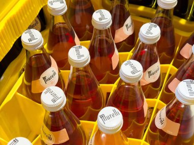 Sarı plastik sandıkta kırmızı sıvı bulunan cam şişelerin yakın çekimi..