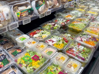 Market koridorunda çeşitli salata ve sebzeler sergileniyor..