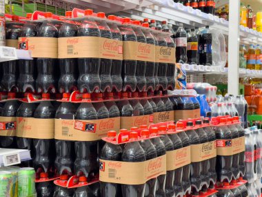 Marketin içecek reyonunda kola şişeleriyle dolu raflar..