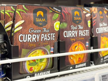 Süpermarket rafında yeşil ve kırmızı Tayland köri ezmesi paketleme.