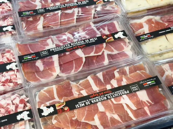 Pazarda çeşitli paketlenmiş prosciutto ve peynir sergileniyor.