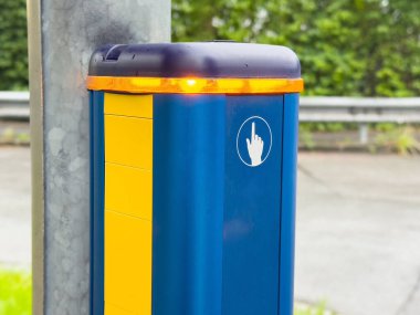 Yol kenarında sarı ve mavi desenli yaya geçiş düğmesi..