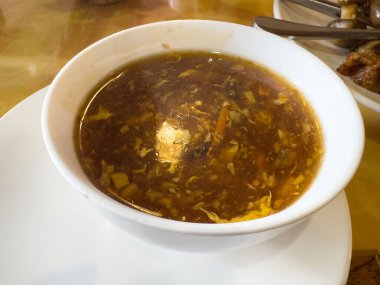 Masadaki beyaz seramik kasede lezzetli sıcak ve ekşi çorba..