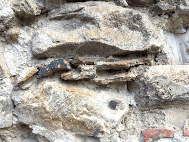 Yıpranmış kaya ve çatlaklara sahip antik taş duvarın yakın çekimi.