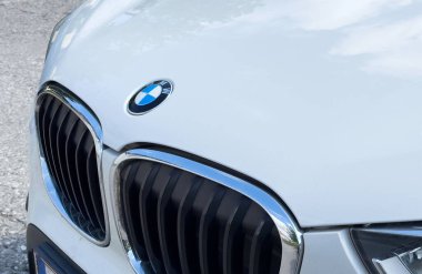 Beyaz lüks araba ön tarafında ikonik BMW logosu ve ızgara tasarımı var..