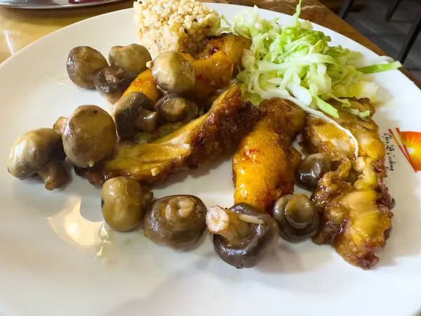 Beyaz tabakta ızgara mantar ve lahana ve kinoalı tavuk..