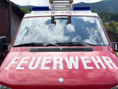 Yansıtıcı bulutları olan kırmızı Avusturyalı itfaiyeci kamyonuna yakın çekim.