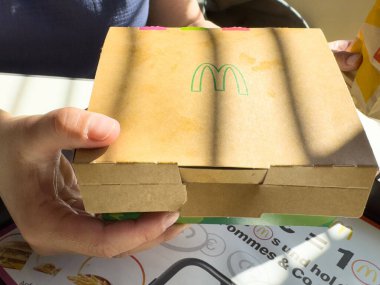 Gün ışığında McDonald 'ın hamburger kutusunu tutan eller..