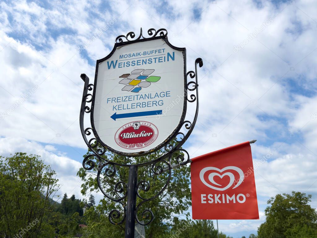 Weissenstein sign and eskimo banner against blue sky in scenic outdoor setting.